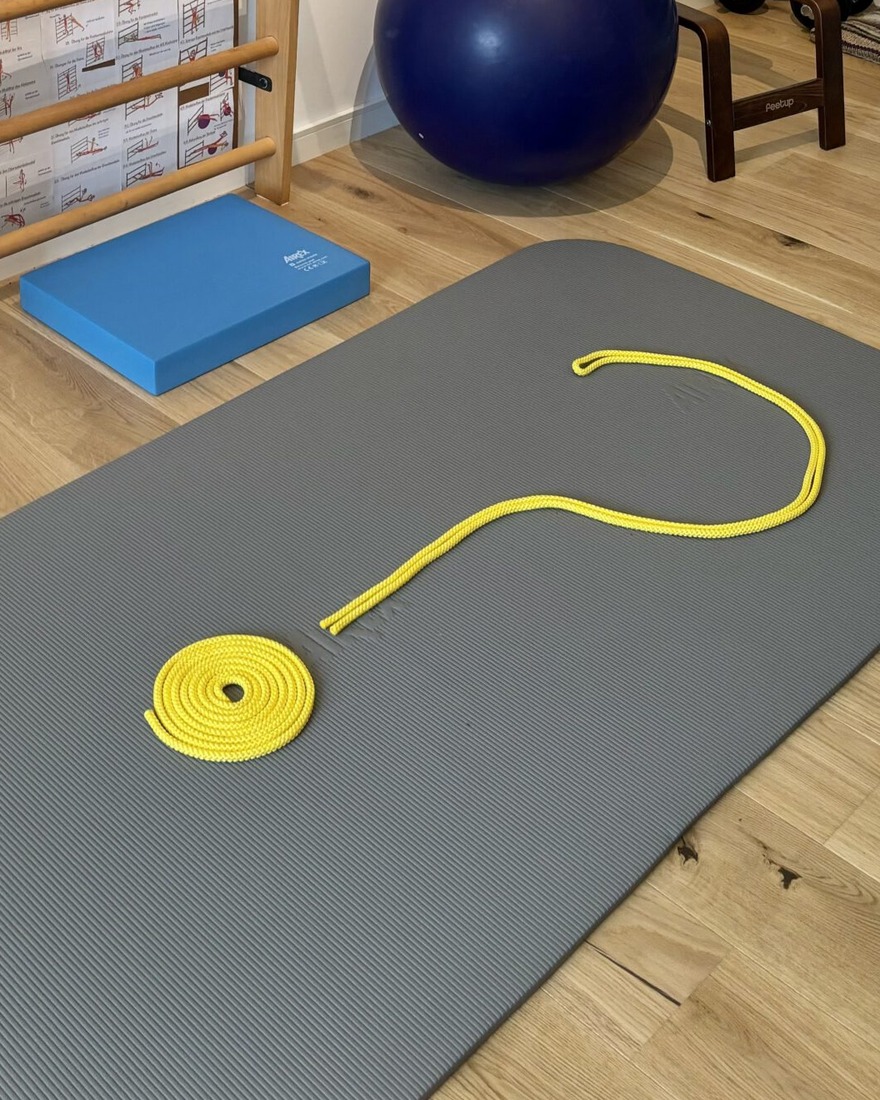 Ein Fragezeichen aus einem gelben Springseil auf der Trainingsmatte im Home-Studio