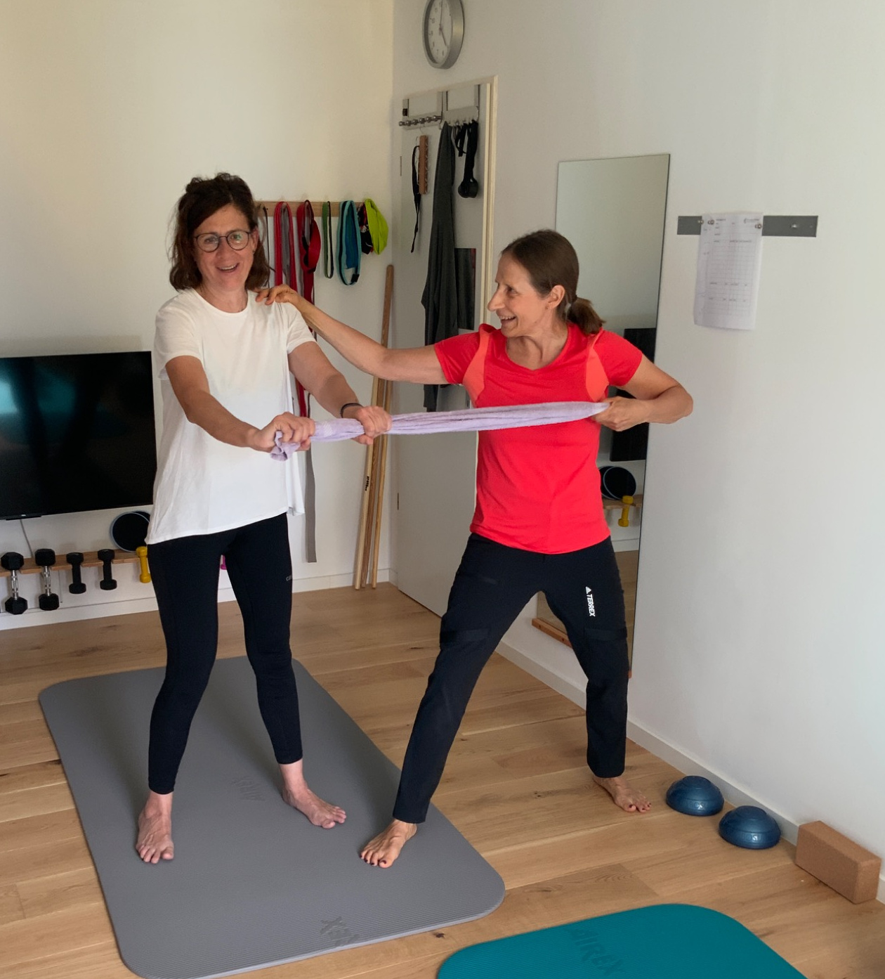 Personal Training in Hitdorf, Rheindorf und Langenfeld: Dr. Annette Schimmel trainiert mit einer Kundin Kraft und Stabilität mit einem Handtuch im Home-Studio