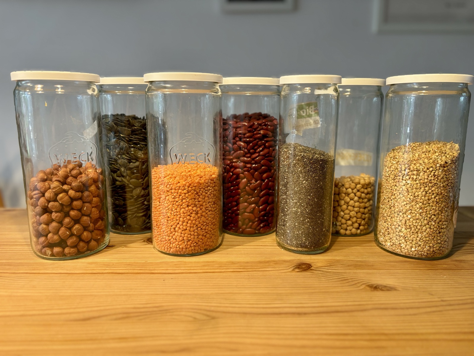 Weck-Gläser mit Haselnüssen, Kürbiskernen, Linsen, Bohnen, Chiasamen, Kichererbsen und Buchweizen als Beispiel für nährstoffdichte Ernährung in den Wechseljahren