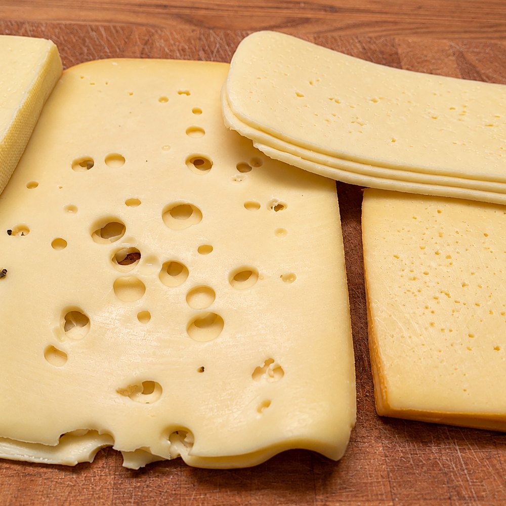 Scheiben von Hartkäse auf einem Holzbrett, Hartkäse ist eine der besten Calciumquellen bei Osteoporose